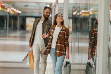 Birlikte, el ele tutuşarak. Genç çift süpermarkette..