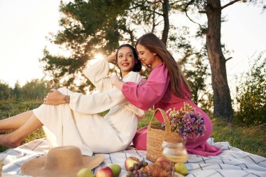 Oturma, bir demet meyve ve çiçek buketi. Lezbiyen çift doğada piknik yapıyor..