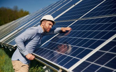 Resmi kıyafetlerle. Gündüz vakti fotovoltaik güneş panelleri olan bir mühendis..