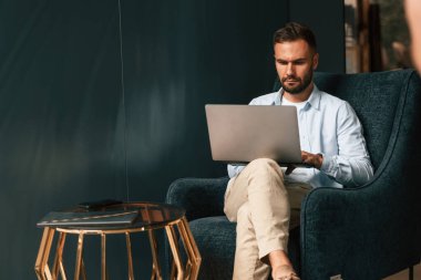 İşadamı dizüstü bilgisayarını kullanarak oturuyor ve çalışıyor..