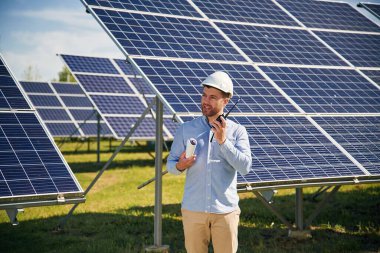 Resmi kıyafetlerle. Gündüz vakti fotovoltaik güneş panelleri olan bir mühendis..