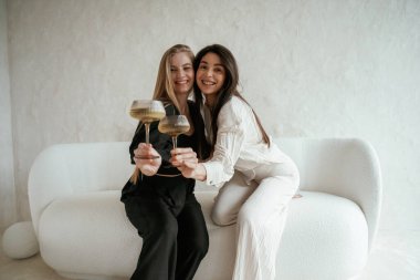 Siyah beyaz giysiler içinde, içkiyle, kutlama yaparak. İki mutlu genç bayan en iyi arkadaş içeride..