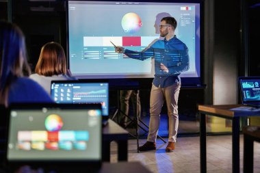 Tasarım araçları. Erkek işletme eğitmeni projektöre karşı, insanlara öğretiyor..