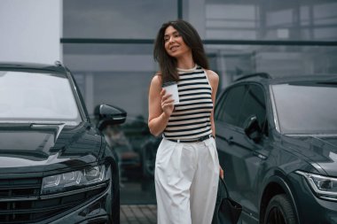 Yürüyen içecekler. Çekici genç bayan dışarıda, yepyeni arabasının yanında..