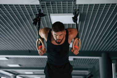 Atletik halkalarda. Güçlü kaslı adam spor salonunda çalışıyor..