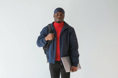 Gümüş renkli dizüstü bilgisayar elinde. Stüdyoda beyaz arka plana karşı siyah adam var..