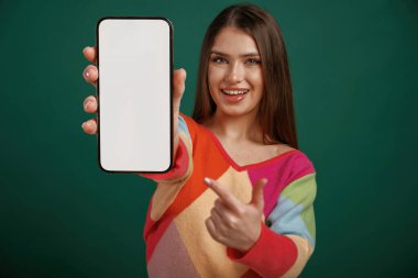 Beyaz akıllı telefon ekranı, mesaj için yer. Genç bir kadın stüdyoda yeşil arka plana karşı duruyor..