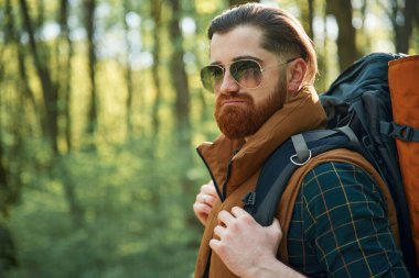 Soğuk güneş gözlükleriyle. Sakallı adam gündüz vakti ormandadır..