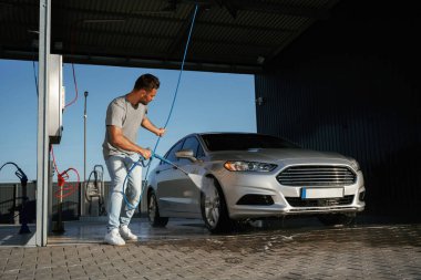 Araba yıkama servisi, adam dışarıda arabasıyla bekliyor..