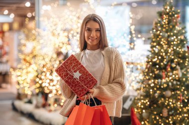 Hediye ellerde. Yeni yıl alışverişi ve hediyeleri. Kadın Noel ağacının yanında..