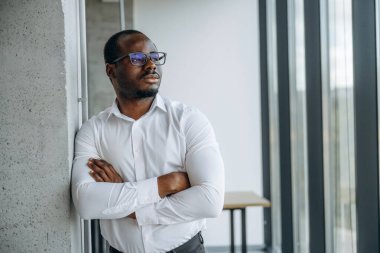 Kollarını kavuşturmuş duruyorsun. İşadamı modern ofiste çalışıyor..