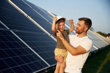 Beyaz başlık. Baba ve küçük oğlu güneş panellerinin yakınındalar..