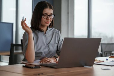Masadaki dizüstü bilgisayarın yanında. Paltolu kadın doktor içeride..