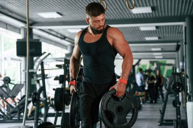 Ağırlık ellerde. Güçlü kaslı adam spor salonunda çalışıyor..