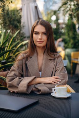 Bardakta taze sıcak içecek. Güzel, genç bir bayan restoranın dışında, masanın yanında..