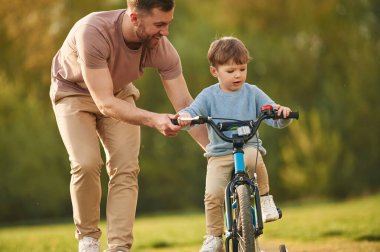Mavi bisiklet, binicilik. Mutlu baba ve oğul yazın sahada eğleniyorlar..