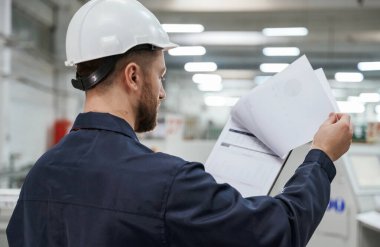 Belgelerin sayfalarını çeviriyorum. Fabrika işçisi kasketli bir şekilde içeride..