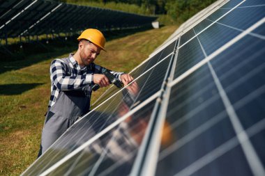 Elde matkap. Gündüz vakti fotovoltaik güneş panelleri olan bir mühendis..