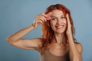 Deride pembe renkli yüz bandı kullanılıyor. Kadın stüdyoda arka planda..