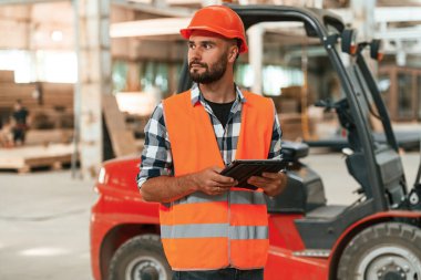 Müdür dijital tabletle ilgileniyor. Ahşap depoda sanayi işçisi..