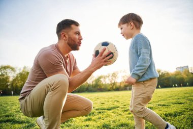 Futbol topuyla. Mutlu baba ve oğul yazın sahada eğleniyorlar..