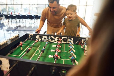 Eğlence anlayışı. Baba ve oğul içeride masa futbolu oynuyorlar..