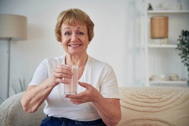 Grip önleyici ilaçla birlikte iç. Yaşlı yaşlı kadın evde, oturma odasında..