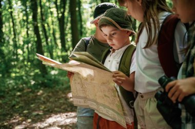 Kağıt harita ellerinde. Çocuklar yazın gündüz vakti ormanda..