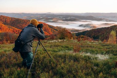 Profesyonel fotoğrafçı tripodun üzerinde kamerayla Karpat dağlarının görkemli manzarasını çekiyor..