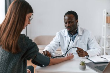 Bir doktor genç bir kadının kan basıncını ölçer..