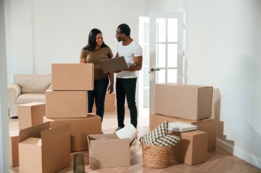 Laptop kullanan kablosuz cihaz. Afrikalı Amerikalı çift yeni eve taşınıyor..