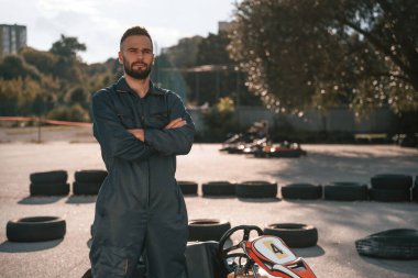 Aracın ve ağaçların karşısında duruyor. Erkekler açık havada, kart yarışı gebeliği..