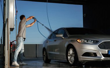 Otomobil yıkama, adam dışarıda arabasıyla bekliyor..