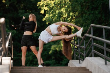 Hazırlanıyor, egzersizleri ısıtıyor. İki sportif kadın açık havada birlikte..