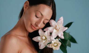 Elinde zambak çiçeği olan bir portre. Genç kadın stüdyoda arka planda..