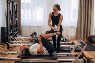 Bacak egzersizi. Kadın eğitmen yaşlı kadına yardım ediyor..