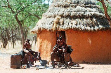 Namibya, Afrika - 14 Haziran 2021: Etnik insanlar, kadınlar eski tarz evlerinin yakınında bir araya geldiler.