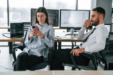 Akıllı telefon kullanarak hisse senedi bilgileri. İki çalışan ofiste birlikte çalışıyor..