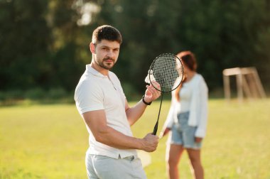 Hafta sonu aktiviteleri. Kadın ve erkek sahada badminton oynuyorlar..