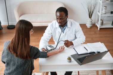 Müşteri hizmetleri. Bir doktor genç bir kadının kan basıncını ölçer..