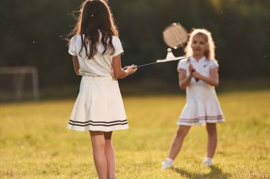 Kızlar badminton oynuyor. Mutlu çocuklar yaz tarlasında.