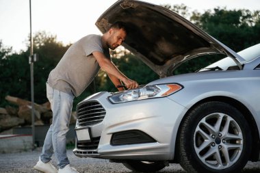 Sorun, bozuk otomobili tamir etmek ve onarmak. Adam dışarıda arabasıyla bekliyor..