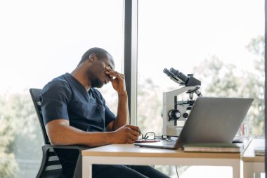 Yorgunum, oturuyorum ve mola veriyorum. Bilim adamı içeride çalışıyor, mikroskop masada..