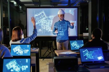 Erkek mimar, insanlar için mavi projektör üzerinde inşaat alanı projesi gösteriyor.