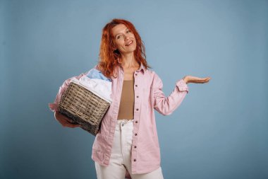 Düşünüyorum, çamaşır sepetinde çamaşır tutuyorum. Kadın stüdyoda arka planda..