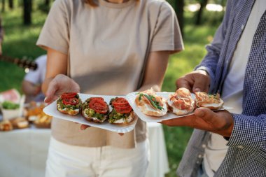 Lezzetli yemekler ellerde. Bir grup arkadaş, ekolojik kutularda yiyeceklerle sahada piknik yapıyorlar..