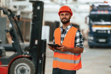 Müdür dijital tabletle ilgileniyor. Ahşap depoda sanayi işçisi..
