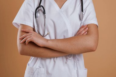 Profesyonel doktor. Kahverengi arka planda duran kadının yakın görüntüsü.