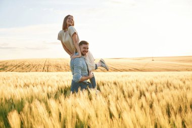Eğleniyor, erkek kadını tutuyor. Güzel bir çift birlikte tarlada..