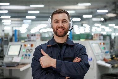 Ayakta ve gülümsüyor. Fabrika işçisi kasketli bir şekilde içeride..